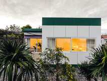 Quinta de Santa Barbara auf Sao Miguel, modernes und gemütliches Ferienhaus mit großem Fenster und grüner Umgebung bei Dämmerung.