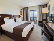 Hotel Marina Atlantico auf Sao Miguel, modernes Zimmer mit Doppelbetten, stilvollem Interieur und Balkon mit Meerblick – komfortabler Rückzugsort für entspannte Urlaubstage.