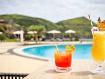 Erfrischende Cocktails am Pool mit Blick auf grüne Hügel – exklusive Unterkunft auf der Insel Terceira.