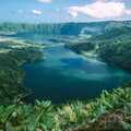Blick von oben auf die zwei unterschiedlich gefärbten Kraterseen von Sete Cidades, umgeben von grünen Hügeln auf der Azoreninsel São Miguel.