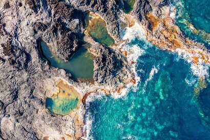 Luftaufnahme der Piscinas Naturais Caneiros bei Mosteiros auf São Miguel mit natürlichen Lavapools und türkisblauem Atlantik.