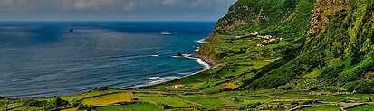 Blick über die grüne Küstenlandschaft von Flores mit steilen Klippen und dem Atlantik im Hintergrund.