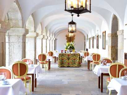 Der Speisesaal einer historischen Pousada mit weiß gedeckten Tischen und altem Mauerwerk