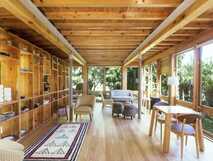 Azul Singular auf der Insel Faial, gemütlicher Lounge-Bereich mit großen Fenstern, Holzbalken und modernen Möbeln, die viel natürliches Licht und einen Blick ins Grüne bieten.