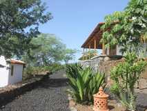 La Fora Ecolodge auf Fogo, idyllische Lodge mit natürlicher Lavaweg-Umgebung und einladender Terrasse im grünen Garten.