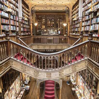 Blick von oben auf die rote Treppe und mächtigen Bücherregalen voller Bücher