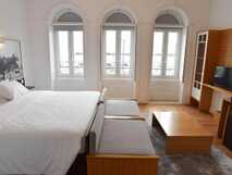 International Azores Boutique Hotel auf Faial, stilvolles Zimmer mit großem Bett, modernem Holzmobiliar und Blick auf den Hafen.