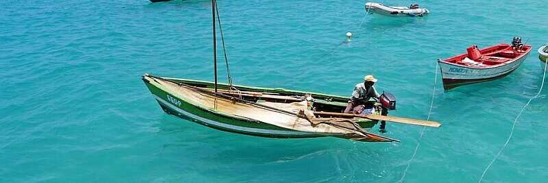 Traditionelle Fischerboote treiben auf dem türkisfarbenen Meer vor der Küste der Kapverden – Sinnbild für das einfache Leben und die gelebte Kommunikation auf den Inseln.