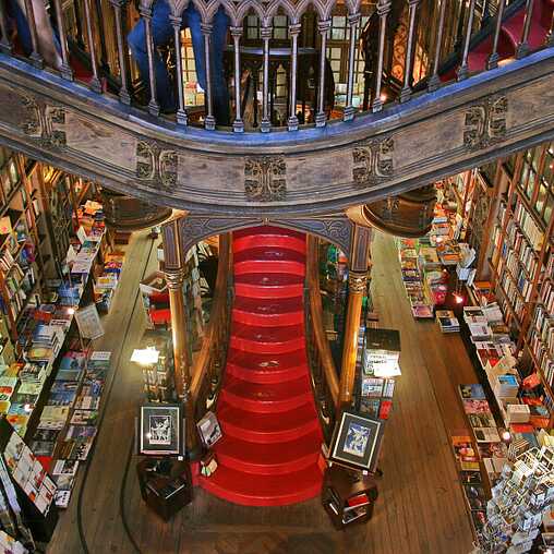 Eine gewaltige rote Treppe umgeben von Büchern im Inneren der Livraria Lello