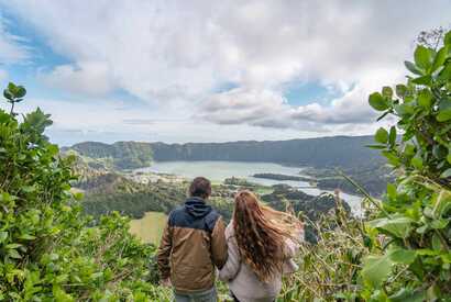 Wanderer genießen den Ausblick über die Vulkanlandschaft der Azoren auf São Miguel – sicherer Aktivurlaub in Portugal.