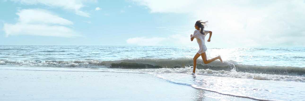 Eine Frau joggt entspannt am Strand auf den Kapverden bei Sonnenschein.