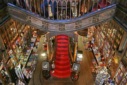 Eine gewaltige rote Treppe umgeben von Büchern im Inneren der Livraria Lello