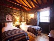 Adegas do Pico – Gemütliches Doppelzimmer im traditionellen Stil mit Natursteinwänden und warmem Holzambiente auf der Insel Pico.