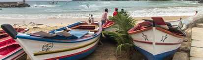 Bunte Fischerboote am Strand von Tarrafal auf Santiago, Kapverden – mit Blick auf die malerische Bucht und Berge im Hintergrund.