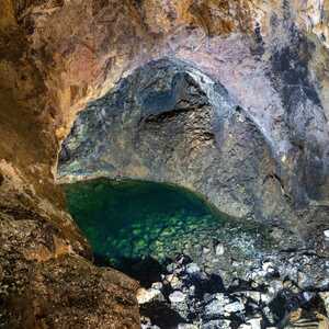 Kleiner unterirdischer See in der Gruta do Natal auf Terceira, umgeben von dunklen Basaltwänden einer vulkanischen Lavaröhre auf den Azoren