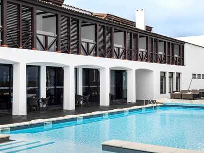 Historisches Hotel mit moderner Poolanlage und dunklen Holzläden auf der Azoreninsel Faial