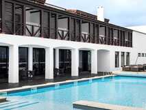 Historisches Hotel mit moderner Poolanlage und dunklen Holzläden auf der Azoreninsel Faial