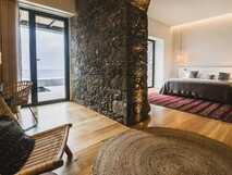 Sensi Azores Nature & Spa auf Sao Miguel – stilvolles Zimmer mit Natursteinwand, gemütlicher Atmosphäre und Meerblick-Terrasse für erholsame Tage.