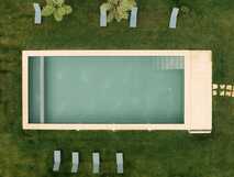 Rechteckiger Swimmingpool im Garten des Villa Camelia Boutique Hotels, umgeben von Liegen und Grün
