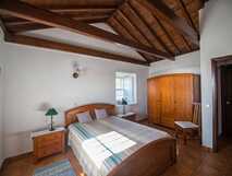 Casas do Capelo, gemütliches Schlafzimmer mit Holzbett, Nachttischen, kleinem Fenster und sichtbaren Holzbalken an der Decke auf Faial.