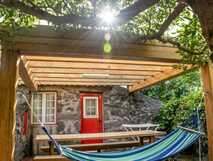 Überdachte Terrasse mit Picknicktisch und Hängematte vor einem Natursteinhaus im Aldeia dos Caldeirões auf São Miguel
