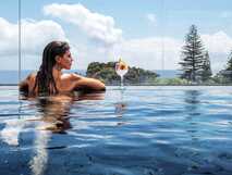Aqua Populo Eco Village auf Sao Miguel, entspannter Moment im Infinity-Pool mit Meeresblick und erfrischendem Cocktail – perfekt für nachhaltigen Urlaub.