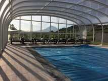 Überdachter Pool mit Liegestühlen und Panorama auf malerischen Vulkan – Entspannung mit atemberaubender Aussicht bei picotours.