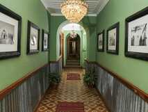 Casa Colonial König auf Fogo – stilvoll eingerichteter historischer Flur mit grün gestrichenen Wänden, nostalgischen Schwarz-Weiß-Fotografien und elegantem Kronleuchter.