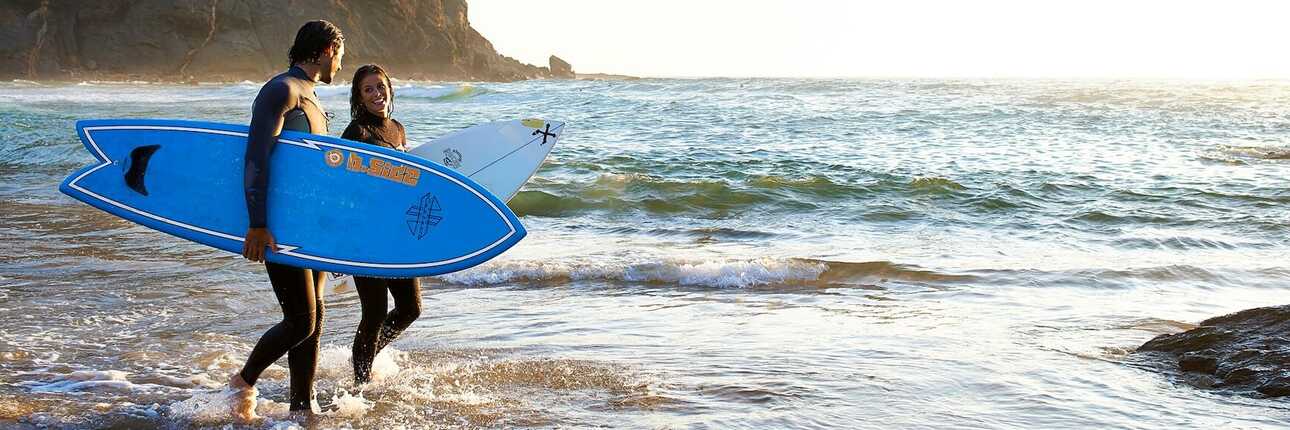 Paar mit Surfbrettern am Strand von Portugal