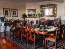 Rustikales Esszimmer mit großem gedecktem Tisch, Holzfußboden und klassischen Gemälden