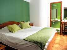 Residencial Alcides auf Sao Miguel, gemütliches Doppelzimmer mit grünem Akzent und modernem Bad – komfortabel und einladend für erholsame Urlaubstage.