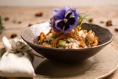 Kreativ angerichtetes vegetarisches Hauptgericht im Restaurant Rotas da Ilha Verde auf São Miguel mit saisonalem Gemüse, cremigem Risotto und essbaren Blüten