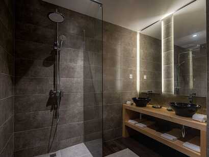 Senhora da Rosa Tradition & Nature Hotel auf Sao Miguel, modernes Badezimmer mit großzügiger Regendusche und stilvollen Waschbecken in natürlichem Ambiente.