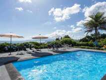 Casa do Monte auf Sao Miguel, entspannter Poolbereich mit Liegestühlen und Sonnenschirmen vor malerischer Atlantik-Kulisse – perfekt für erholsame Urlaubsmomente bei picotours.