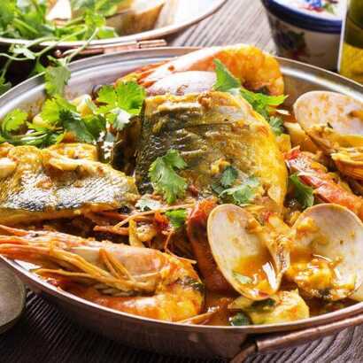 Portugiesisches Cataplana-Gericht mit Fisch, Garnelen und Muscheln in würziger Sauce.