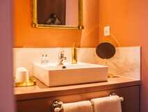 Waschbecken mit Spiegel, goldenen Armaturen und warmem Licht in einem stilvollen Badezimmer