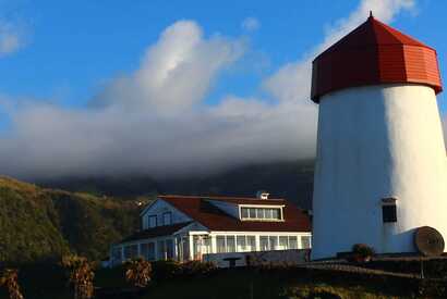 Historische Windmühle von Mosteiros auf São Miguel mit Blick auf die Vulkanlandschaft der Azoren.