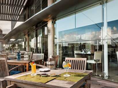 Hotel Marina Atlantico auf Sao Miguel, einladende Terrasse mit gemütlichen Holzmöbeln und erfrischenden Getränken für entspannte Stunden mit Meerblick.