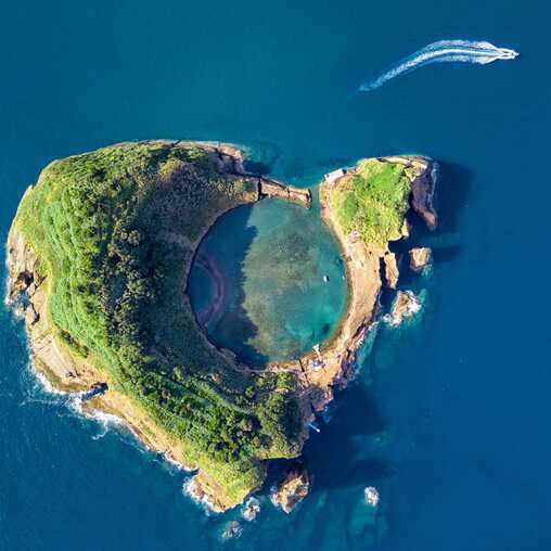 Luftaufnahme der Ilhéu de Vila Franca do Campo mit kreisrunder Lagune und Boot beim Verlassen der Insel