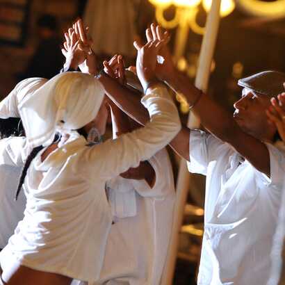 Traditionelle Tänzer:innen in weißer Kleidung führen einen kulturellen Tanz bei Nacht auf den Kapverden auf.