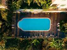 Blick aus der Vogelperspektive auf den von tropischen Pflanzen umgebenen Pool des Villa Alto Boutique Hotels