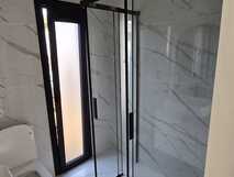 Moderner, heller Badezimmerbereich mit eleganter Glasdusche und stilvollen Marmorfliesen – Komfort und Design für Ihre Traumreise bei picotours.