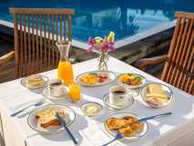 Antillia Hotel Apartments auf Sao Miguel, genussvolles Frühstück im Freien am Pool mit frischem Orangensaft, Kaffee und regionalen Spezialitäten, perfekt für entspannte Urlaubsmomente.