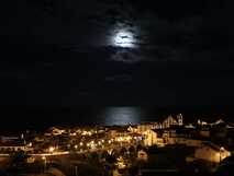 The Lince Nordeste Country & Nature Hotel auf Sao Miguel, stimmungsvolle Nachtaufnahme mit Mondlicht über dem ruhigen Küstenort, perfekt für entspannte Urlaubsmomente.