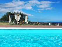 Infinity-Pool der Alluar Lodge mit Blick auf das Meer und gemütlicher Pergola mit weißen Vorhängen auf der Azoreninsel Pico