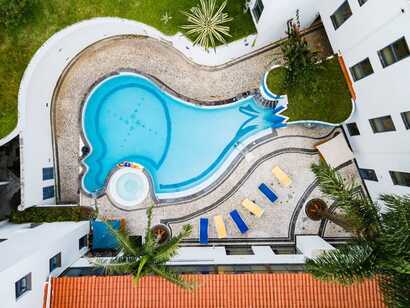 Hotel do Mar auf Sao Miguel, einladender Außenpool mit Sonnenliegen inmitten grüner Anlage – perfekter Ort zur Erholung bei Picotours.