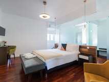 Helles Schlafzimmer mit stilvollen Möbeln, Glastrennwand und Holzboden.