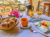 Casa Colonial König auf Fogo – Köstliches Frühstück mit frischen Brötchen, Ei, Käse, Obst und frisch gepresstem Saft.