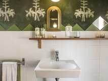 Estrela do Atlantico auf Faial, stilvolles Badezimmer mit grün-weißer Wandgestaltung, kleinem Spiegel und Waschbecken.