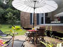 Quinta da Mo – Gemütliche Terrasse mit Liegestühlen und Sonnenschirm in grüner Gartenanlage für entspannte Urlaubsmomente auf São Miguel.